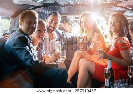 Group of party people in a limo drinking looking at the camera
