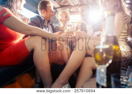 Group of party people in a limo drinking looking at the camera