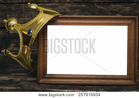 Blank Photo Frame Border With Copy Space And Golden Crown Above On Wooden Wall Background.