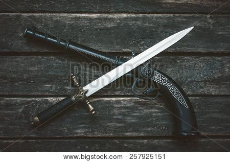 Musket Gun And Dagger Knife On Wooden Table Background.