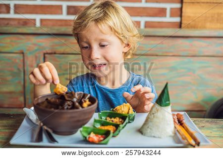 Boy Eats In A Cafe. Lifestyle. A Dish Consisting Of Rice, Fried Fish With Wood Mushrooms And Differe