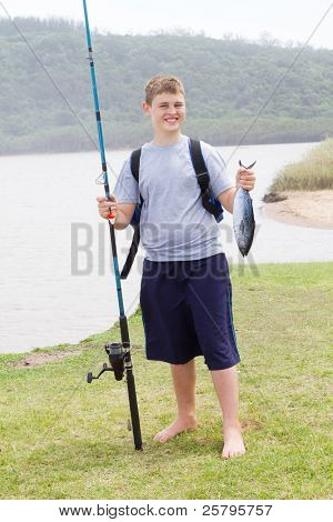 szczęśliwy teen chłopiec trzyma wędkę i ryby złapał