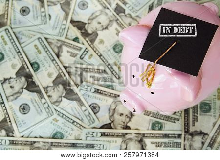 Piggy With In Debt Graduation Cap On Money