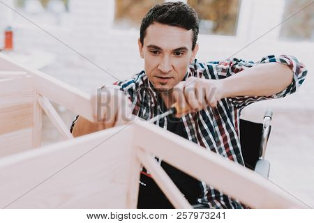 Young Man On Wheelchair Assembling Wooden Bookshelf At Home. Wooden Bookcase. Selfmade Furniture. Wh