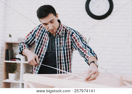 Young Man Assembling Wooden Bookshelf At Home. Wooden Bookcase. Selfmade Furniture. Man And Hobby. W