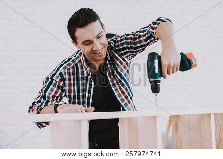 Young Man Assembling Wooden Bookshelf At Home. Wooden Bookcase. Selfmade Furniture. Man And Hobby. W