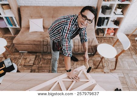 Young Man Assembling Wooden Bookshelf At Home. Wooden Bookcase. Selfmade Furniture. Man And Hobby. W