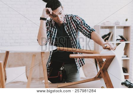 Young Man Assembling Coffee Table And Stools. Furniture Fittings. Engineer With Tool. Young Man At H