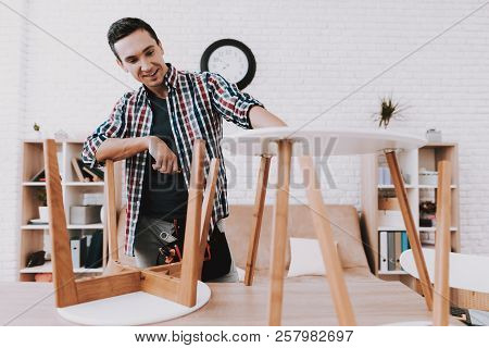Young Man Assembling Coffee Table And Stools. Furniture Fittings. Engineer With Tool. Young Man At H