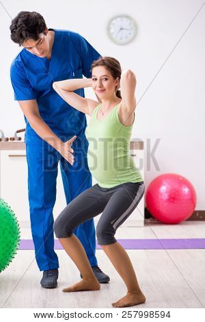 Pregnant woman doing physical exercies with instructor