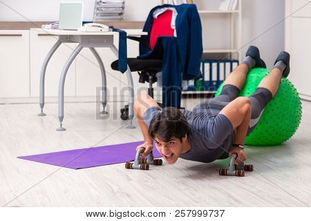 Young male employee exercising in the office
