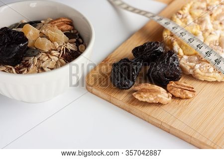 Muesli With Pumpkin Seeds, Sunflower Seeds And Flax Seeds In A White Bowl, With Two Corn Pies, Pecan