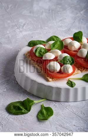 Toasts With Mozzarella, Tomatoes And Spinach In A White Plate
