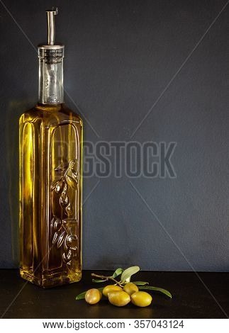 Glass Bottle Of Olive Oil With Olives And On Olive Branch.