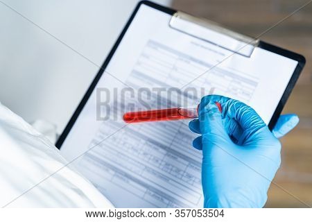 Closeup Of Microbiologist Or Medical Worker Hand With Blue Surgical Gloves Marking Blood Test Result