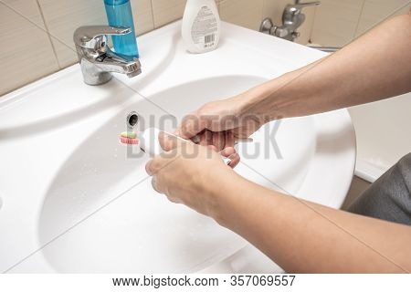 Female Hands Squizzing Toothpaste Out Of A Tube In Bathroom During Her Daily Routine