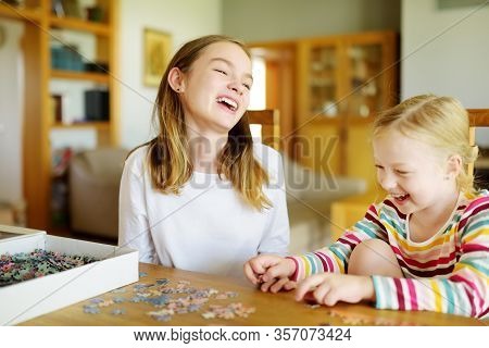 Cute Young Girls Playing Puzzles At Home. Children Connecting Jigsaw Puzzle Pieces In A Living Room