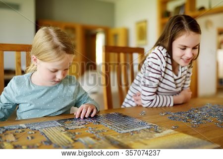 Cute Young Girls Playing Puzzles At Home. Children Connecting Jigsaw Puzzle Pieces In A Living Room