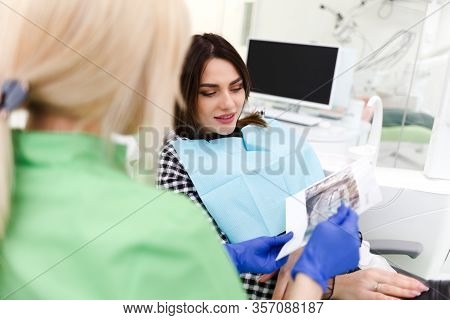 Dental Clinic Doctor Shows A Panoramic X-ray Picture To His Patient. Doctor Explains To Her Patient 