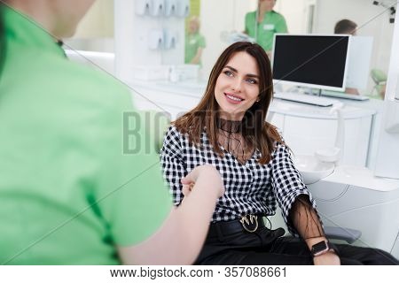 Pretty Woman Greets With Dentist Doctor. Dental Clinic Patient Sitting In A Chair Shaking Hands With