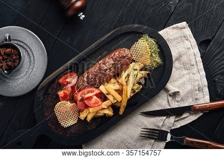 The Finished Dish With Kebab Meat And Potatoes Is Decorated With Greens And Vegetables. The Concept 
