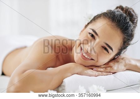 Happy Attractive Young Woman Lying On Bed In Spa Salon And Waiting For Relaxing Back Nassage