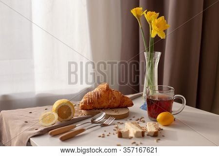 In The Room On The Table Serving Breakfast With A Cup Of Tea, Croissants, Lemons And Yellow Narcis I