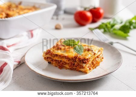 Piece Of Tasty Hot Lasagna Served With A Basil Leaf On A Gray Plate. Italian Cuisine, Menu, Recipe. 