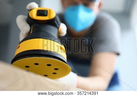 Male Handy Man Hold Yellow Grinder With Disc Sander In Hand Closeup Background. Professional Educati