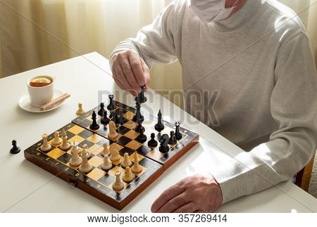 A Man In A Medical Mask In Quarantine Plays Chess. Quarantine, Covid-19, Self-isolation Concept. Hor