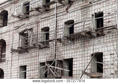 Brick Wall Of Old Destroyed House Without Windows With Wooden Broken Scaffold. Abandoned Repair Of U
