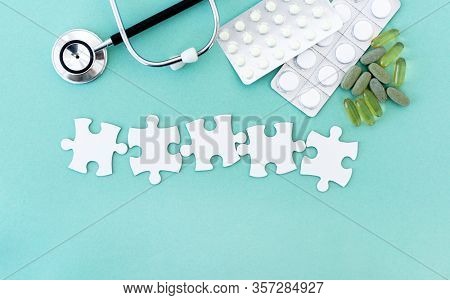Puzzle pieces in row for lettering next to pills and phonendoscope