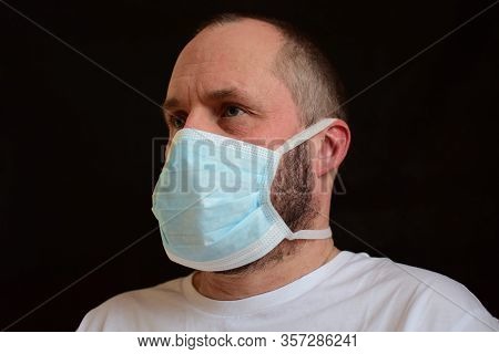 Man In A Medical Mask On A Black Background. Portrait, Close-up. Bokeh. Selective Focus.