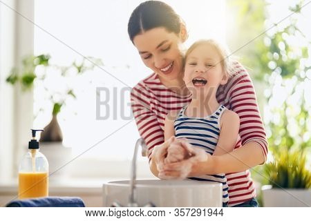 A cute little girl and her mother are washing their hands. Protection against infections and viruses. 