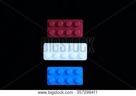 Blue And Red Toys With A White Paracetamol Tablet Representing The Dutch Flag On A Black Background.