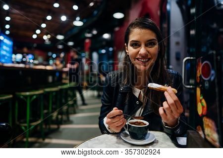 Smiling Young Woman Eating Traditional Spanish Churros With Sugar Dipped In Hot Chocolate Sauce  In 