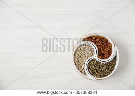 Peeled Sunflower Seeds, Pumpkin Seeds And Raisins Lie On A White Table In A Beautiful Round Plate Di