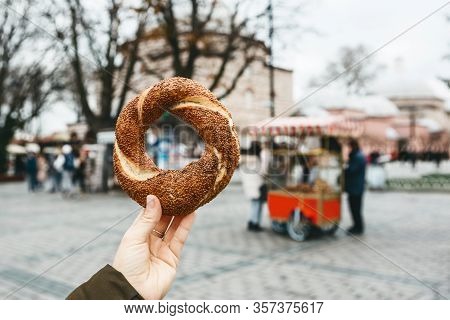A Person Is Holding A Traditional Turkish Bagel Simit On The Background Of A Street Stall Selling Si