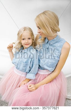Beautiful Young Blonde Mom And Her Charming Daughter In The Same Romantic Clothes. Happy Motherhood.