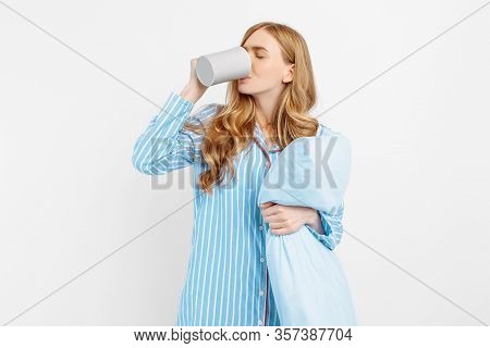 Beautiful Girl In Striped Pajamas, With A Cup In Her Hands , Drinking Coffee Or Tea In The Early Mor