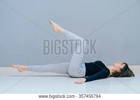 Woman Working Out At Home, Doing Yoga Exercise On Wooden Floor, Lying In Shavasana Corpse Or Dead Bo