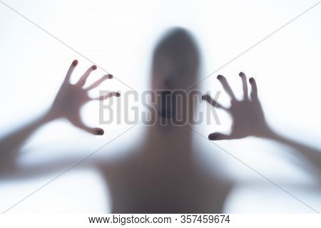 Blurred Silhouette Shadow Of A Terrorific Body Shape Behind A White Background Showing Head And Cree