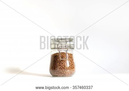 Buckwheat Is Tightly Closed In A Glass Bowl. One Jar Stands On A White Background In Daylight With S