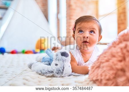 Beautiful infant happy at kindergarten around colorful toys lying on blacket