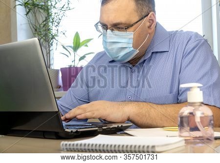 Quarantine Due To The Coronavirus Pandemic. Business Man Working From Home, Wear A Protective Mask. 