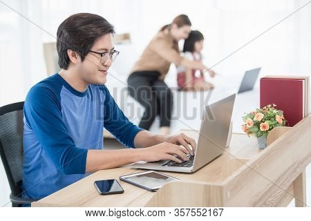 Asian Businessman And Father Working At Home With Notebook Computer, Tablet, And Smartphone While Hi