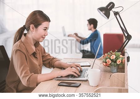 Asian Businesswoman Using Notebook Computer Working From Home While Her Husband Doing Her Work With 