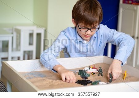 The Boy With Glasses Is Sand Therapy On The Table With Light.