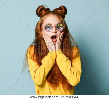 Much Surprised Amazed Red-haired Teenager Girl In Stylish Round Glasses And A Yellow Sweatshirt Gasp