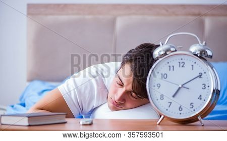 Man in bed frustrated suffering from insomnia with an alarm cloc